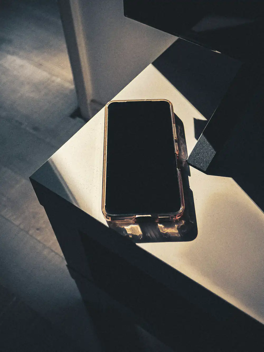 A phone lying face up on a low stand in a shaft of early light