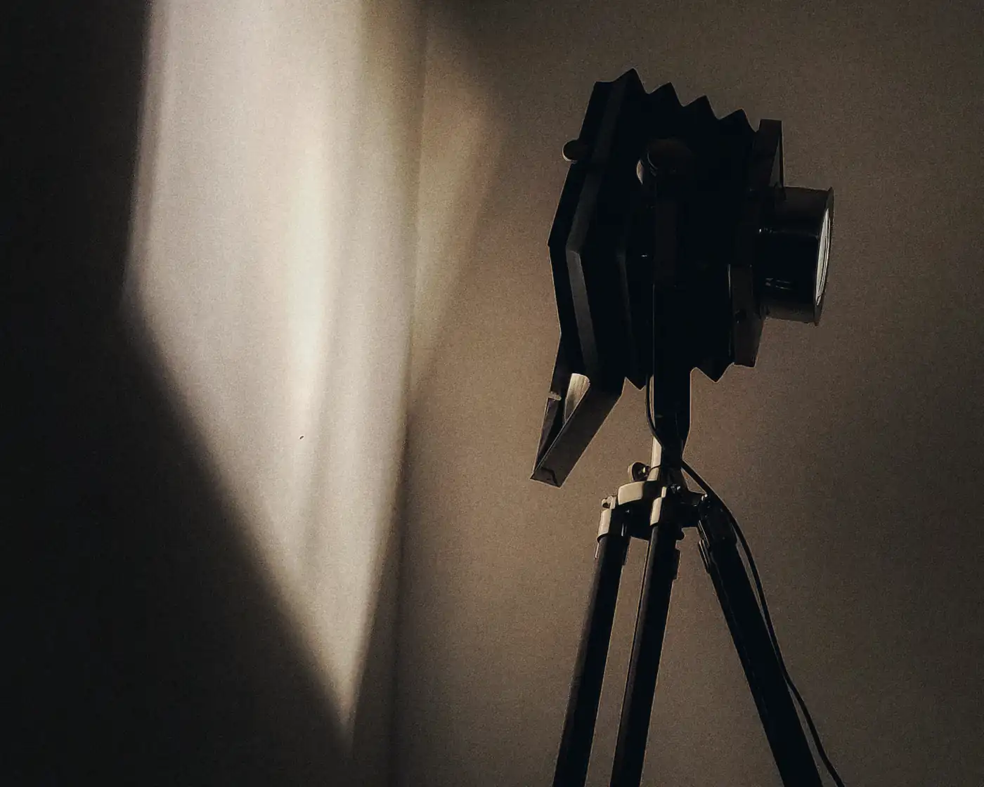 A camera on a tripod facing a lit wall, waiting for the take